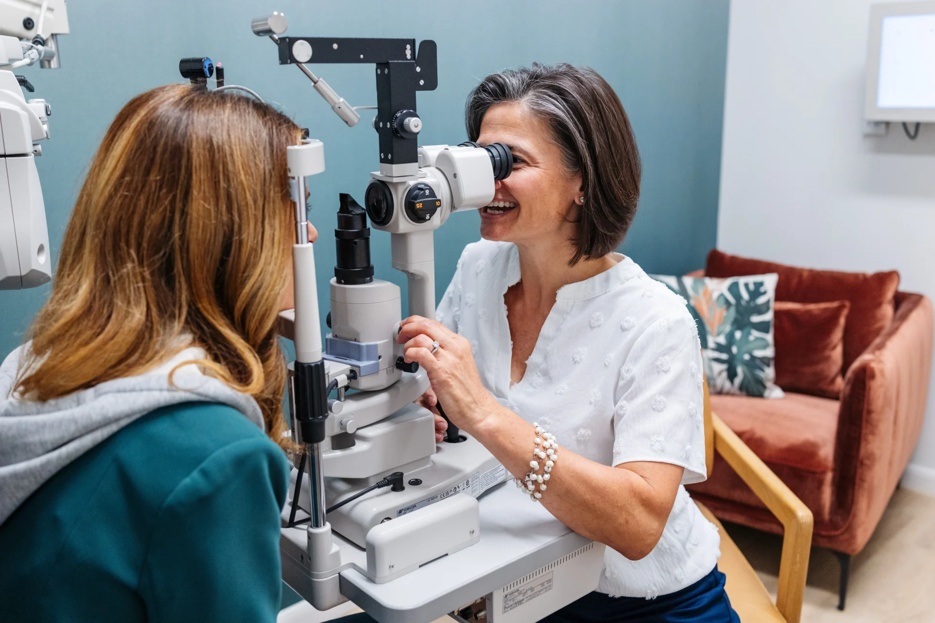 An optometrist uses a slit lamp to examine a patient's eyes in a modern clinic.